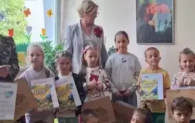 grupa dzieci pozuje do zdjęcia niekt&oacute;re dzieci trzymają dyplomy w tle elegancko ubrana pani