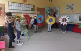 czworo dzieci trzyma duże kwiaty wykonane z papieru i obręczy obok dzieci w ż&oacute;łtych opaskach i pani nauczycielka w stroju pszczelarza
