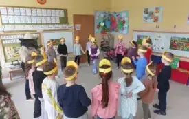 dzieci w ż&oacute;łtych opaskach i pani nauczycielka w stroju pszczelarza stoją w kole