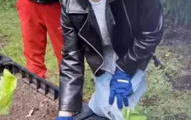 dziewczynka i chłopiec stoją przy rabacie z roślinami dziewczynka trzyma szpadelek