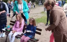 panie zaplatające warkoczyki dziewczynkom w tle ludzie na pikniku