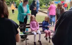 ludzie na pikniku panie zaplatające warkoczyki dziewczynkom