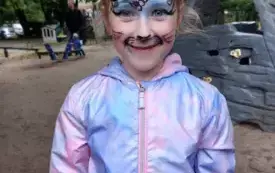 dziewczynka z buzią pomalowaną na kotka pozuje do zdjęcia 