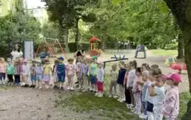 duża grupa dzieci w ogrodzie przedszkolnym tworzą p&oacute;łkole
