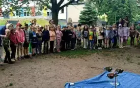 niebieska płachta rozłożona na ziemi na niej akcesoria alchemiczne w tle duża grupa dzieci