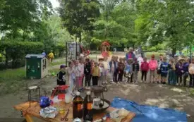 na pierwszym planie st&oacute;ł zastawiony akcesoriami alchemicznymi w tlr grupa dzieci ogr&oacute;d przedszkolny