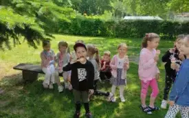 dzieci z lodami siedzą na ławce inne stoją