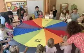 pani nauczycielka wraz z dziećmi i rodzicami trzymają chustę animacyjną