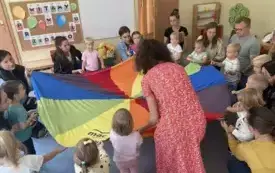 pani nauczycielka wraz z dziećmi i rodzicami trzymają chustę animacyjną