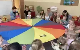 rodzice z dziećmi siedzą dokoła chusty animacyjnej
