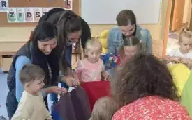 pani nauczycielka wraz z dziećmi i rodzicami trzymają chustę animacyjną
