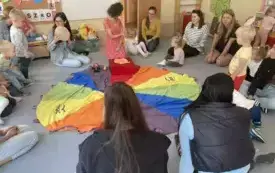 pani nauczycielka wraz z dziećmi i rodzicami siedzą dokoła chusty animacyjnej