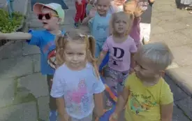 dzieci stoją przed przedszkolem przygotowane do spaceru