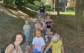 dzieci na spacerze przed nimi kuca pani nauczycielka