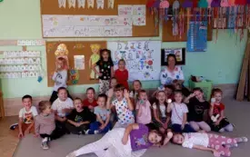 dzieci wraz z panią nauczycielką pozują do zdjęcia grupowego w tle dekoracja związana z dniem kropki