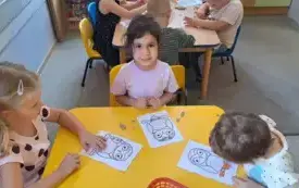trzy dziewczynki siedzą przy stoliku na kt&oacute;rym leżą kartki z szablonami s&oacute;w