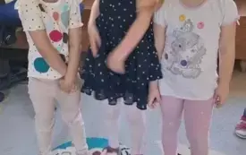 trzy dziewczynki stoją na dywanie przed nimi konstrukcja z kolorowych kubeczk&oacute;w
