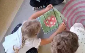 troje dzieci siedzi na dywanie dziewczynka układa puzzle z pask&oacute;w muchomor w trawie