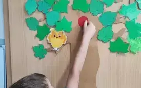 chłopiec przykleja kropkę do dekoracji drzewa