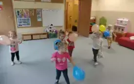 dzieci stoją na dywanie i trzymają kolorowe balony