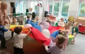 dzieci wsp&oacute;lnie z panią trzymają chustę animacyjną na kt&oacute;rej są balony