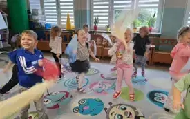 grupa dzieci na sali gimnastycznej w ruchu trzymają kolorowe chustki