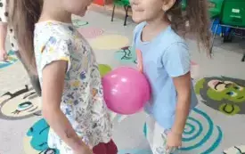 dziewczynki w parze trzymają balon między brzuchami