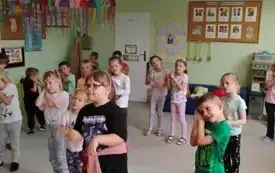dzieci stoją na sali i pokazują ruch złożone ręce pod uchem