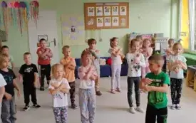 grupa dzieci rozstawiona na sali pokazują ruch rękami