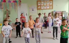 grupa dzieci rozstawiona na sali pokazują ruch rękami