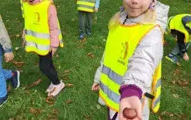 dzieci w kamizelkach odblaskowych dziewczynka pokazuje do zdjęcia kasztana
