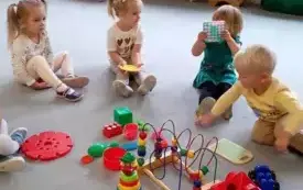 dzieci siedzą na dywanie przed nimi leżą zabawki edukacyjne