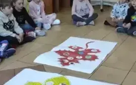 dzieci siedzą na podłodze przed nimi leżą dwa plakaty z liśćmi ż&oacute;łtym i brązowym