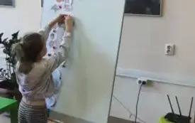 dziewczynka przypina obrazek do tablicy na kt&oacute;rej wiszą k&oacute;łka z motywami jesiennymi