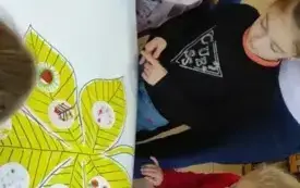 dzieci siedzą przed plakatem z ż&oacute;łtym liściem na kt&oacute;rym przyklejone są ich rysunki na małych okrągłych karteczkach