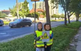 dw&oacute;ch chłopc&oacute;w stoi pod znakiem uwaga dzieci chłopcy trzymają obrazek z takim znakiem