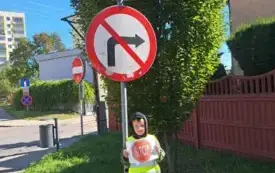 chłopiec stoi pod znakiem drogowym stop i zakaz skrętu chłopiec trzyma obrazek ze znakiem stop