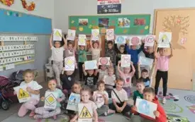 dzieci w klasie pozują do zdjęcia grupowego dzieci trzymają obrazki r&oacute;żnych znak&oacute;w drogowych