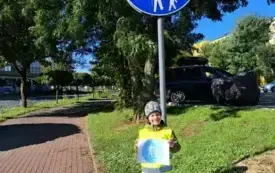 chłopiec stoi pod znakiem deoga dla pieszych/ droga dla rower&oacute;w chłopiec trzyma obrazek tego znaku