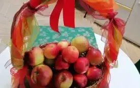 koszyk udekorowany kokardami w jesiennych kolorach w nim jesienne jabłka