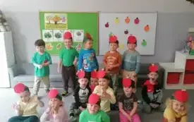 dzieci w opaskach z czerwonymi jabłkami pozują do zdjęcia grupowego w tle dekoracja na dzień jabłka