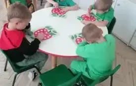 dzieci przy stolikach kolorują szablony jabłek w białe kropki