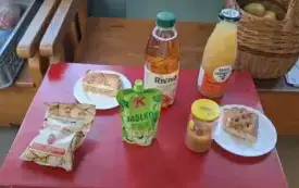 na czerwonym stoliku leżą suszone jabłka w torebce dwa soki dwa rodzaje szarlotki i musy jabłkowe