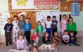 dzieci wraz z panią pozują do zdjęcia grupowego w tle dekoracja dzień jabłka