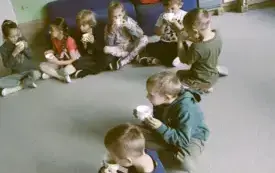 dzieci siedzą na dywanie z kubeczkami