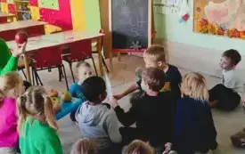 pani nauczycielka opowiada dzieciom o r&oacute;żnych odmianach jabłek dzieci siedzą na dywanie jabłka leżą na niebieskim stoliku