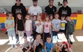 grupa dzieci pozuje do zdjęcia za nimi stoją czterej panowie z akademii fabryka hokeja