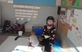 chłopiec w stroju przeznaczonym do gry w hokeja za nim kuca chłopiec trzymający kij do hokeja