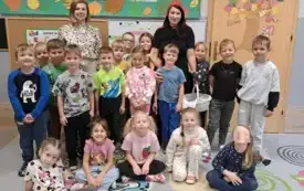 dzieci pozują do zdjęcia grupowego wśr&oacute;d nich stoi pani nauczycielka i pani w stroju czerwonego kapturka