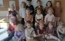 dzieci pozują do zdjęcia przed nimi stoi koszyk z kasztanami w tle dekoracja dzień kasztana